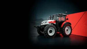 En Steyr Plus-traktor avbildet mot en dramatisk mørk bakgrunn, som fremhever dens moderne design og teknologiske avanserte funksjoner.