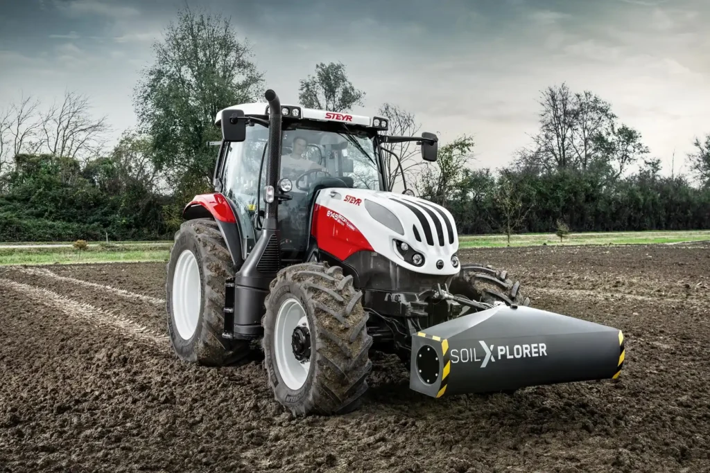 Steyr Profi traktor utstyrt med SoilXplorer jordscanner, kjørende på en åker under overskyet himmel.