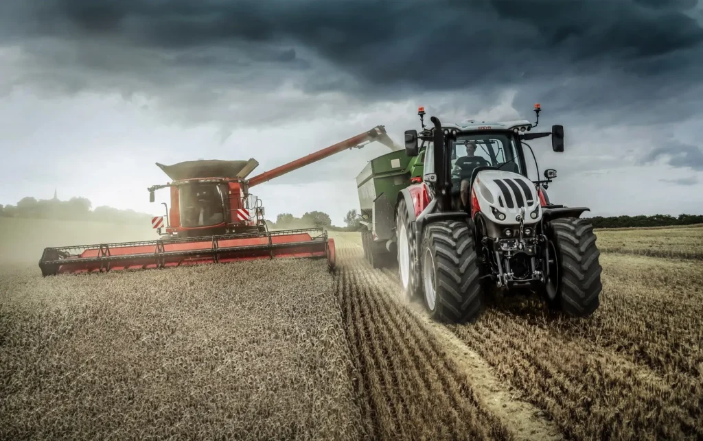 Steyr Terrus traktor jobber i samarbeid med en Case skurtresker på et stort jorde.