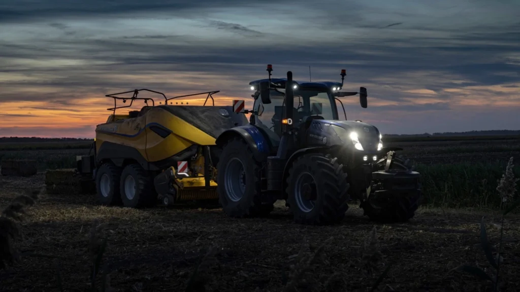 En New Holland T7 LWB-traktor som trekker en gul henger langs en landevei, som viser kombinasjonen av transportkapasitet og kjørekomfort.